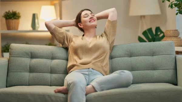 mulher descansando em sofá após limpar a casa com aspirador