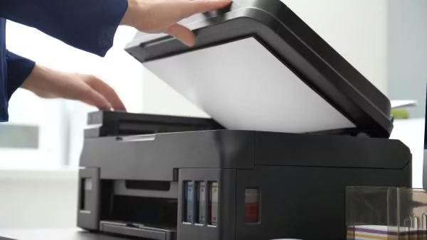 mulher colocando folhas em branco na impressora para imprimir