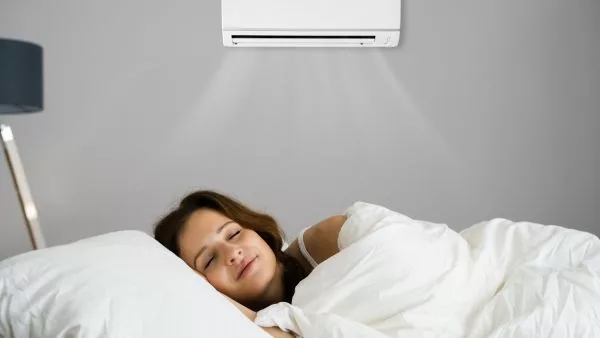 mulher dormindo em ambiente refrescado por ar condicionado