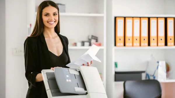 mulher feliz com papeis tirados da impressora em maos