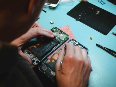 Tecnico em manutencao de celulares fazendo o conserto de um smartphone em sua bancada